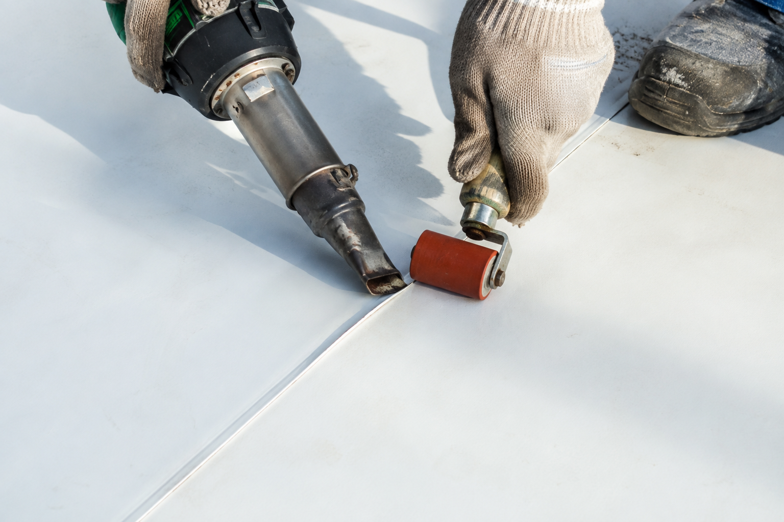 Commercial roofer heat welding a thermoplastic roofing membrane